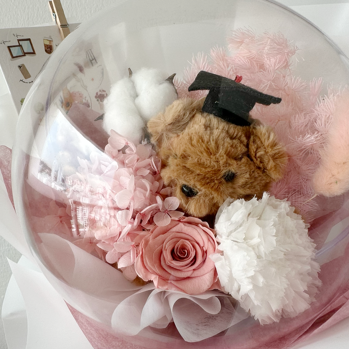 Pink teddy bear with flower bouquet.